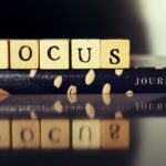 Wooden blocks spelling 'FOCUS' placed on a patterned journal, symbolizing clarity, intention, and a commitment to mindful growth.