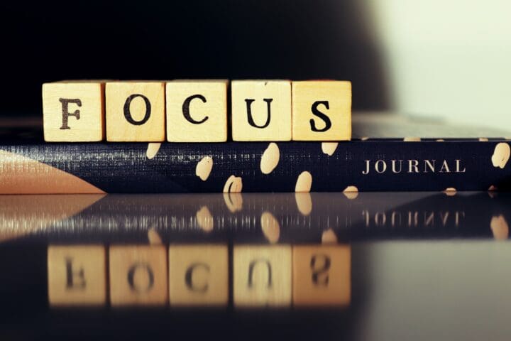 Wooden blocks spelling 'FOCUS' placed on a patterned journal, symbolizing clarity, intention, and a commitment to mindful growth.