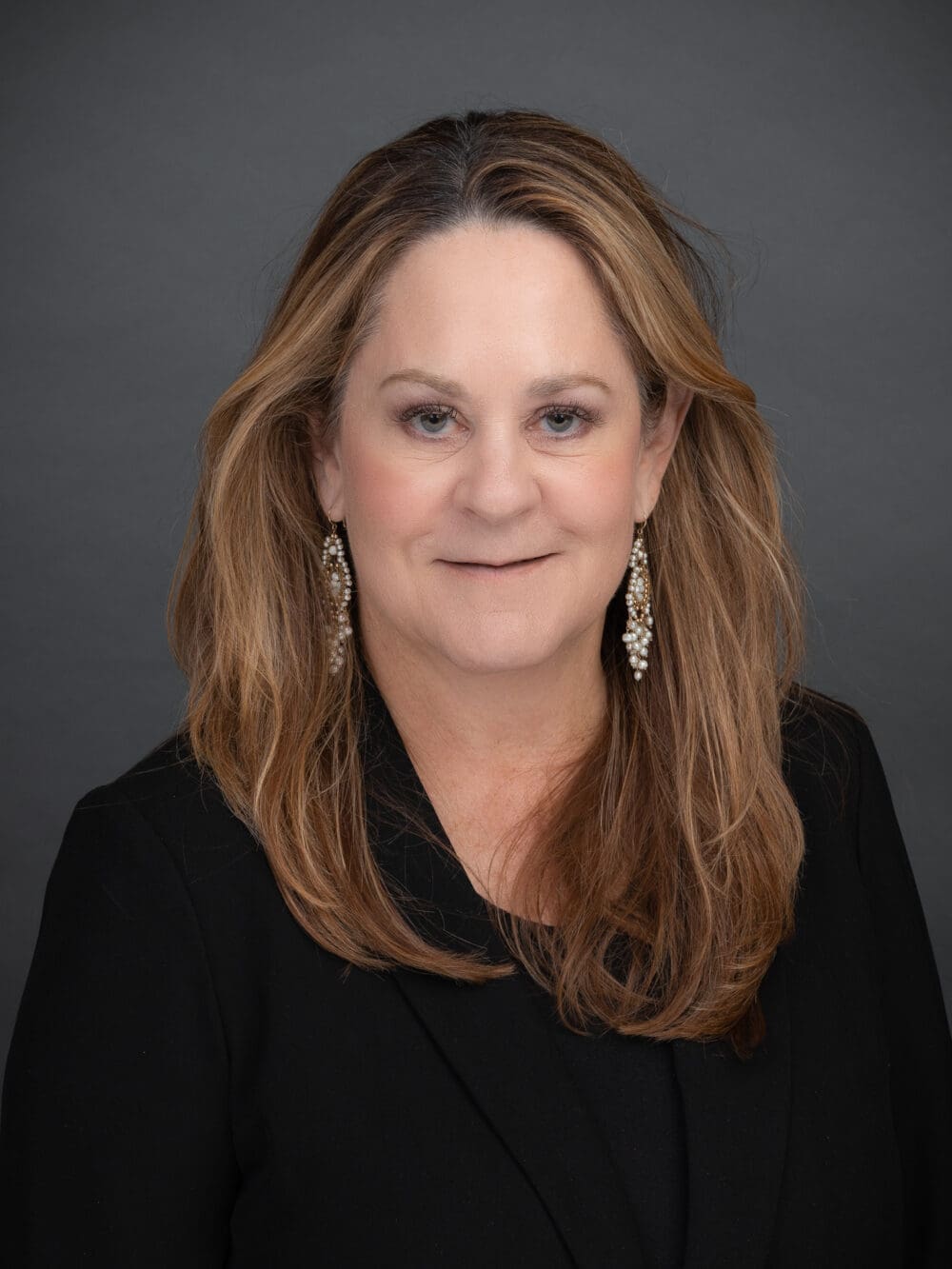 Professional headshot of Josie Correa, a distinguished industry professional in real estate, wearing a black blazer and silver earrings, with a confident and approachable expression.